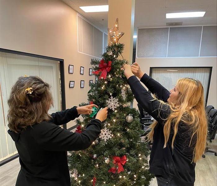 2 SERVPRO staff putting decorations on the xmas tree